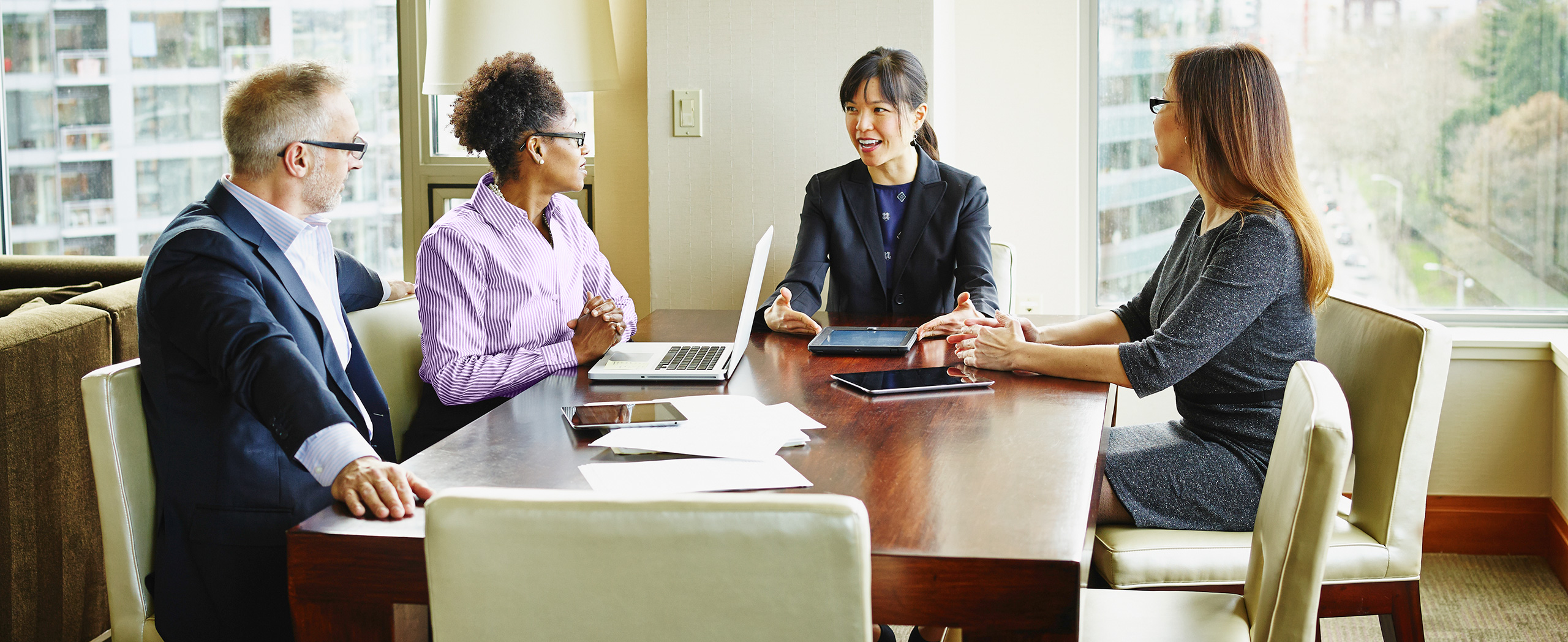 Four executives gather at a conference table to discuss talent optimization strategies.